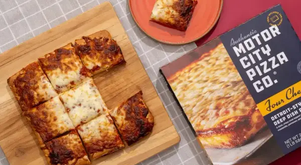 Pokrojona na kwadraty, gorąca pizza mrożona z boxa Motor City Pizza Co. na desce.