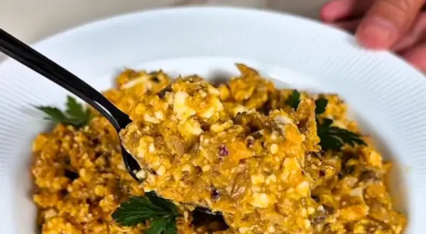 Pyszna pasta z makreli i twarogu, idealna na kanapki. Na czarnej łyżce widać kawałki ryby i sera, ozdobione natką pietruszki.