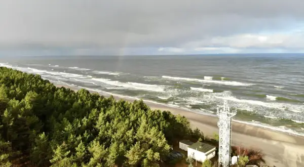 Plaża Kąty Rybackie z wieżą widokową i lasem sosnowym. Na niebie tęcza.