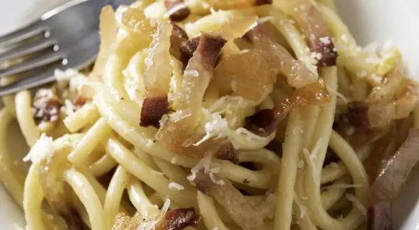 Ein Teller Pasta mit knusprigen Speckwürfeln, die zeigen, was ist Guanciale: luftgetrockneter Schweinebackenspeck, der für den authentischen Geschmack sorgt.