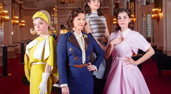 Vier Frauen in farbenfrohen Outfits, die den musical dress code verkörpern. Eine in Gelb, eine in Blau, eine in gestreiftem Oberteil und eine in Rosa.