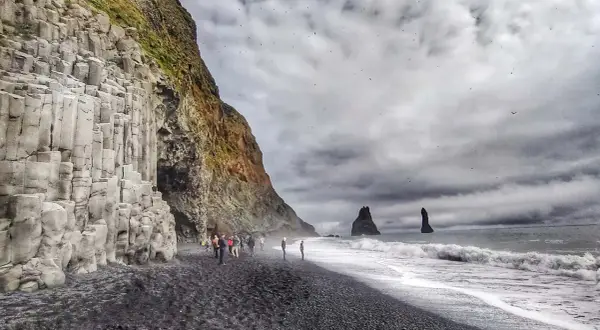 Niesamowita czarna plaża Islandia z bazaltowymi kolumnami i skalnymi formacjami w morzu.