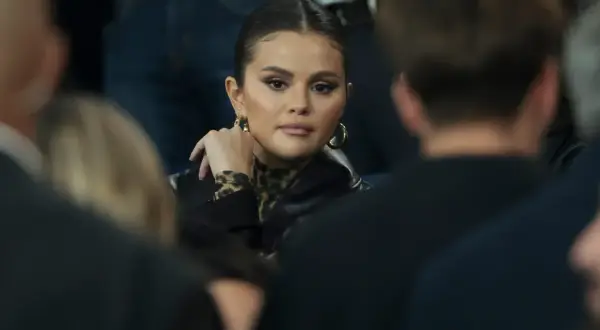 Selena Gomez w czarnej kurtce i bluzce w panterkę, z dłonią opartą o policzek. Fani spekulują o jej ciąży.
