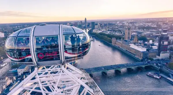 Widok z kapsuły London Eye na Tamizę i Parlament. Ludzie podziwiają panoramę Londynu o zachodzie słońca.