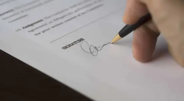 Dłoń podpisuje dokument. Złożenie podpisu może być początkiem sprawy sądowej, czyli pozwu.