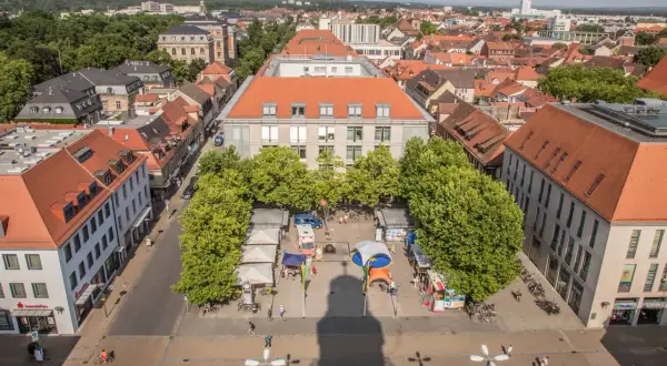 Marktplatz in Erlangen mit Ständen und Bäumen. Ein Schatten wirft sich über den Platz, vielleicht ein Geheimtipp für Fotografen.