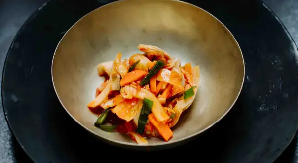 Frisch zubereitetes asiatisches Essen: Kimchi mit Karotten und Frühlingszwiebeln in einer Schüssel.