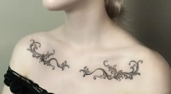 Delikatny tatuaż ornament damski na obojczykach, przypominający koronkę.