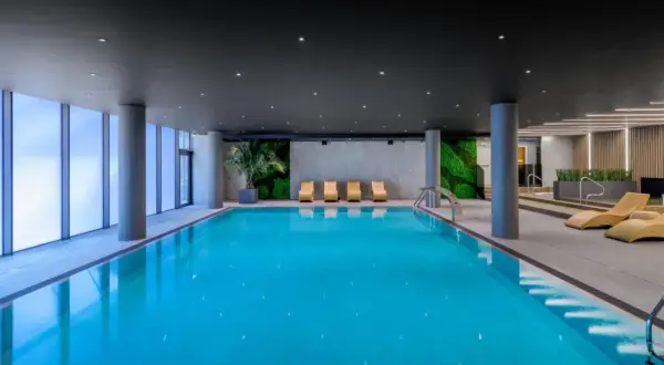Basen w AC Hotels Krakow. Relaks przy basenie z widokiem na zielone ściany i nowoczesne leżaki.