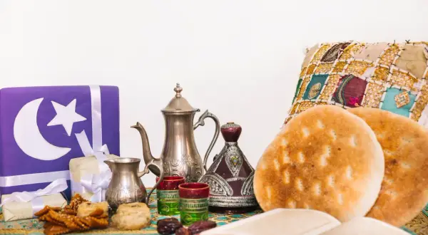 Przygotowania do iftaru: ozdobne prezenty, tradycyjny czajniczek, daktyle, pieczywo i książka.
