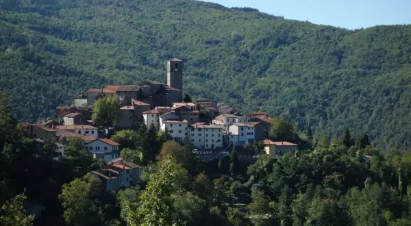 Village de San Marcello Pistoiese niché sur une colline verdoyante, avec son clocher dominant les toits de tuiles rouges.