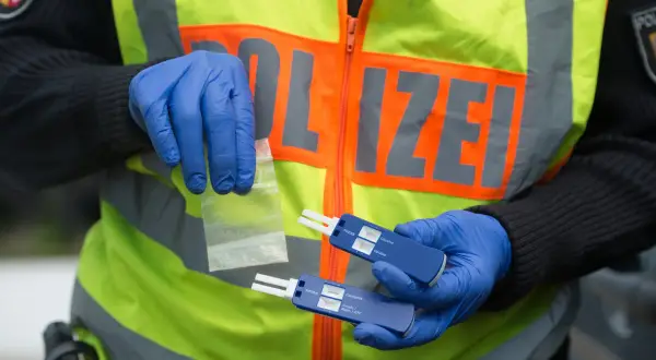 Polizist mit Handschuhen hält Drogenprobe und Tests für Drogen am Steuer.