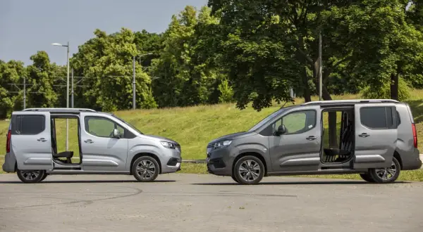 Dwa samochody Toyota Proace City Long w kolorach srebrnym i grafitowym stoją obok siebie z otwartymi drzwiami, ukazując wnętrze.