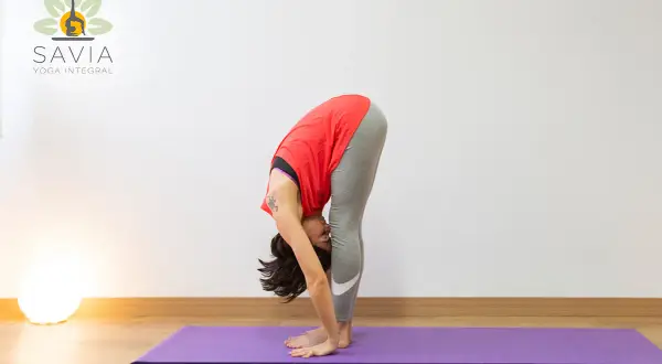 Mujer en postura de Uttanasana yoga, estirando su cuerpo hacia abajo.