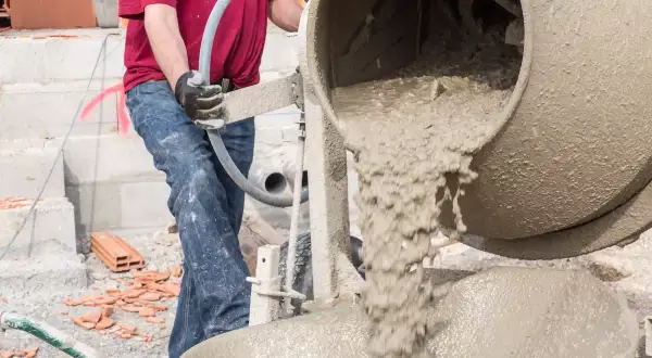 Robotnik miesza chudy beton, dbając o właściwe proporcje składników.