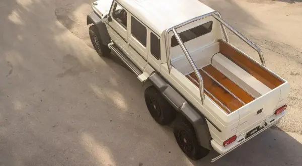 Biały Mercedes 6x6 z drewnianą paką, gotowy na każdą przygodę.