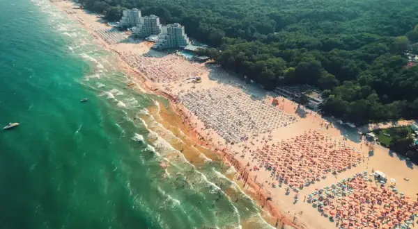 Tłok na plaży podczas wycieczki do Bułgarii. Tysiące parasoli i ludzi kąpiących się w morzu.