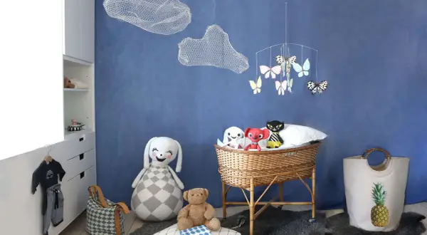 En barnkammare med virka moln i taket. En korgvagga med leksaker, en stor virkad kanin och en nallebjörn.