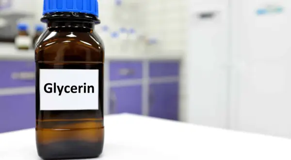 Braune Glasflasche mit blauem Deckel, beschriftet mit "Glycerin". Dieses Glycerin tierisch ist ein wichtiger Bestandteil in vielen Produkten.