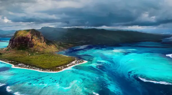 Podwodny wodospad w **Oceania** przy Le Morne Brabant, Mauritius. Turkusowa woda, góra i chmury.