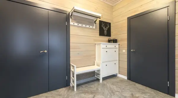 Stylowa aranżacja mieszkania 30m2: ciemne drzwi, biała szafka na buty z ławką i wieszak.