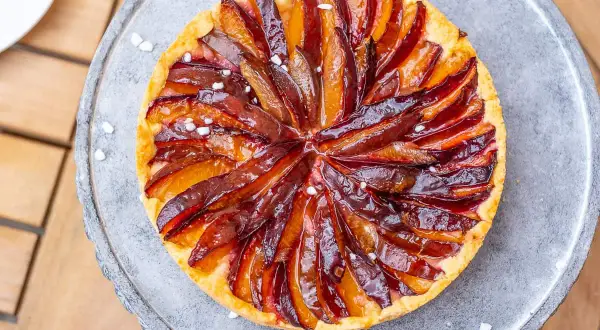 Ein köstlicher Zwetschgenkuchen auf Hefeteig, mit saftigen Pflaumenstücken und einem glänzenden Zuckerguss, verlockend präsentiert.
