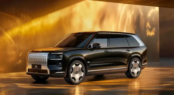 Elegancki, ciemny SUV Zeekr 9X z chromowanym grillem i futurystycznymi felgami, prezentowany w złotym, oświetlonym wnętrzu.