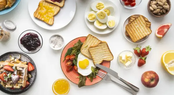 Un uovo al tegamino con pomodorini e toast, waffle con fragole, uova sode, frutta e marmellata: una colazione salata sana e gustosa.