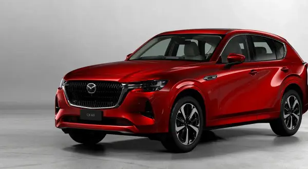 Elegancka, czerwona Mazda CX-60 3.3 Diesel prezentuje swoje dynamiczne linie na tle jasnego studia.
