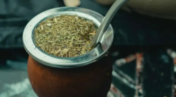 Ein traditioneller Mate-Tee-Becher aus Leder, gefüllt mit getrockneten Mate-Blättern und einer Metall-Bombilla.