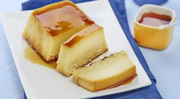 Un délicieux flan au lait concentré, parfait pour une recette flan lait concentré Nestlé. Servi sur une assiette blanche avec un coulis de caramel.