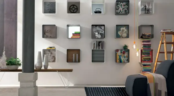 Moderna parete con mensole quadrate, alcune decorate, altre contenenti libri e oggetti, per arredare con stile.