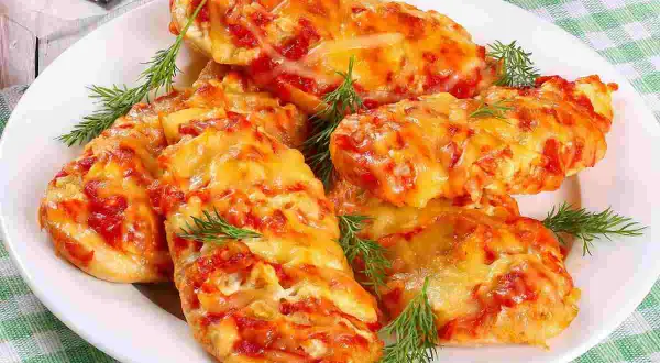 Delizioso petto di pollo alla pizzaiola, cotto al forno con pomodoro e formaggio filante, guarnito con aneto fresco.