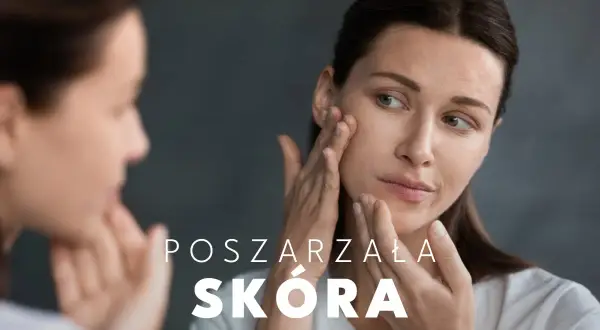 Kobieta z uwagą ogląda swoją poszarzałą cerę w lustrze, dotykając policzka.