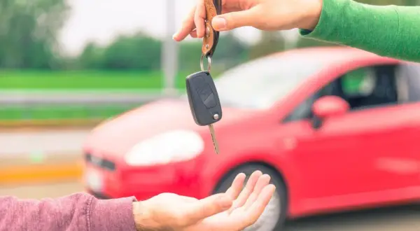 Passaggio di chiavi auto, un gesto che simboleggia cosa serve per vendere auto: fiducia e un nuovo inizio su quattro ruote rosse.