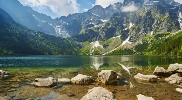 Piękna trasa nad Morskie Oko. Jezioro otoczone skalistymi szczytami Tatr, z zielonymi lasami i kamienistym brzegiem.