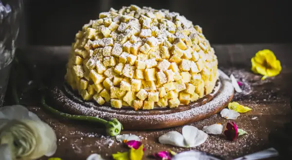 Torta mimosa, una delizia soffice ricoperta di cubetti di pan di Spagna e zucchero a velo, pronta per essere gustata.