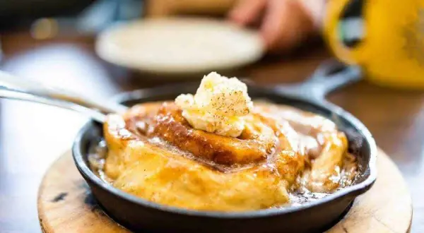 Ein warmer Zimtschnecken-Auflauf in einer Gusseisenpfanne, gekrönt mit Butter. Perfekt, um den Zimtgeschmack zu neutralisieren und den Genuss zu steigern.