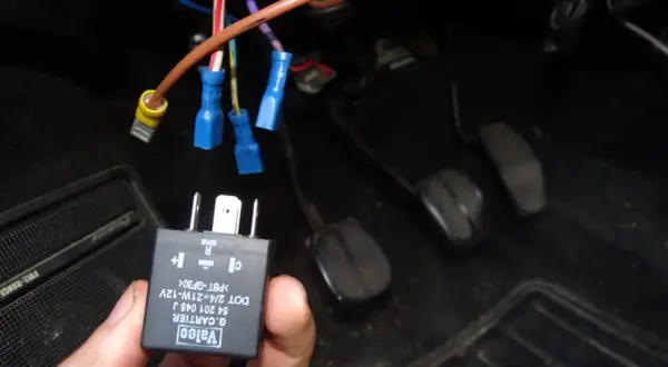 Main tenue, un relais Valeo pour clignotant fonctionne par intermittence. Des fils électriques sont connectés sous le tableau de bord.