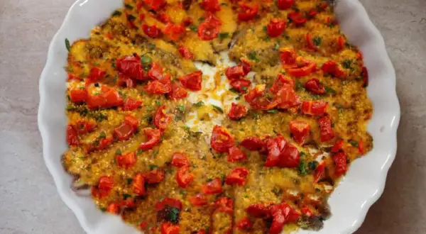 Alici al forno dorate e succulente, ricoperte di pomodorini freschi e pangrattato croccante. Un piatto semplice e gustoso.