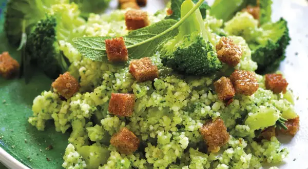 Un gustoso cous cous con broccoli, crostini dorati e foglie di menta fresca, un piatto colorato e salutare.