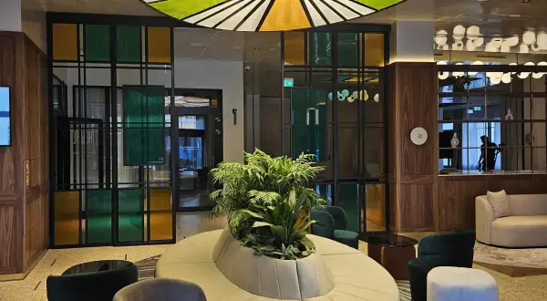 Nowoczesne wnętrze z designerską sofą i roślinnością. Kolorowe witraże i okrągły plafon tworzą niepowtarzalny klimat w grand hotelu Wrocław.
