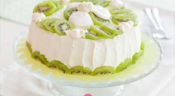 Tort ozdobiony plasterkami kiwi i bezą. Świeże dekoracje z kiwi na torcie dodają mu lekkości i koloru.