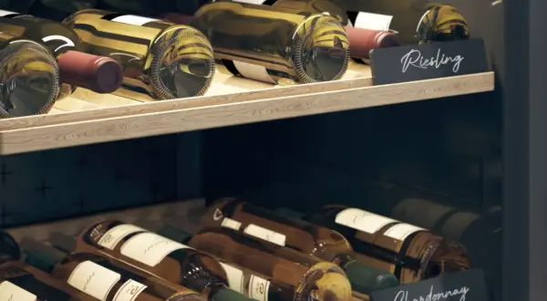 Drewniane półki piwniczki na wino z butelkami Riesling i Chardonnay. Idealne miejsce, jak przechowywać wino w butelkach.