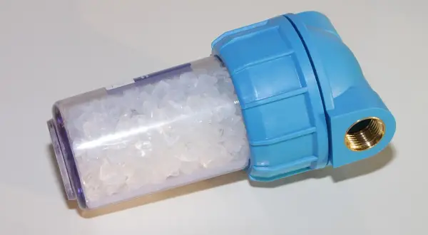 Filtre bleu transparent rempli de cristaux pour l'adoucissement de l'eau.