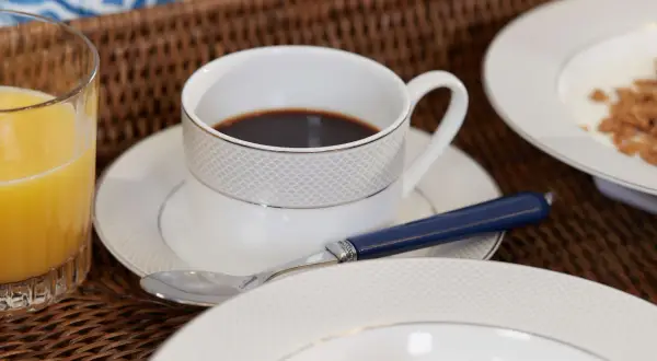 Frukostbricka med kaffe, juice och flingor. En kopp kaffe med en sked, perfekt för att njuta av morgonen. Undrar hur många koppar kaffe per paket?