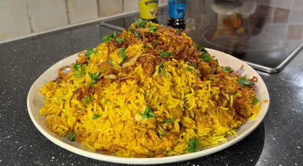 En stor portion gyllene biryani med kyckling, toppad med krispig lök och färsk koriander. Ett perfekt biryani recept för en festmåltid.