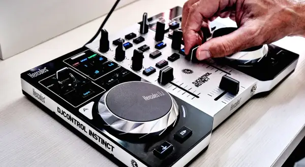 Dłoń DJ-a manipuluje pokrętłem na konsoli Hercules DJControl Instinct.