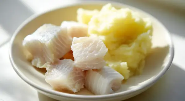 En tallrik med bitar av torsk bebis och potatismos.