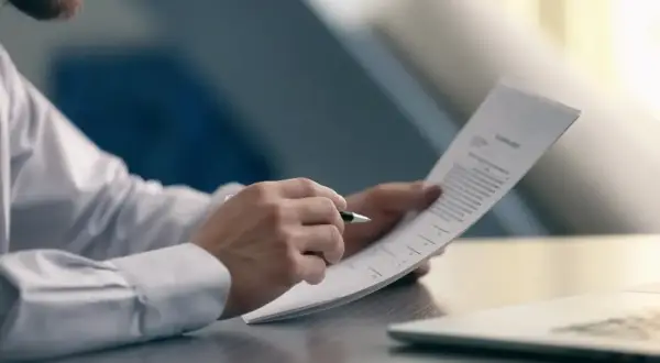 Mężczyzna w białej koszuli analizuje dokument, sprawdzając warunki, kiedy pracodawca nie musi wypłacić odprawy.